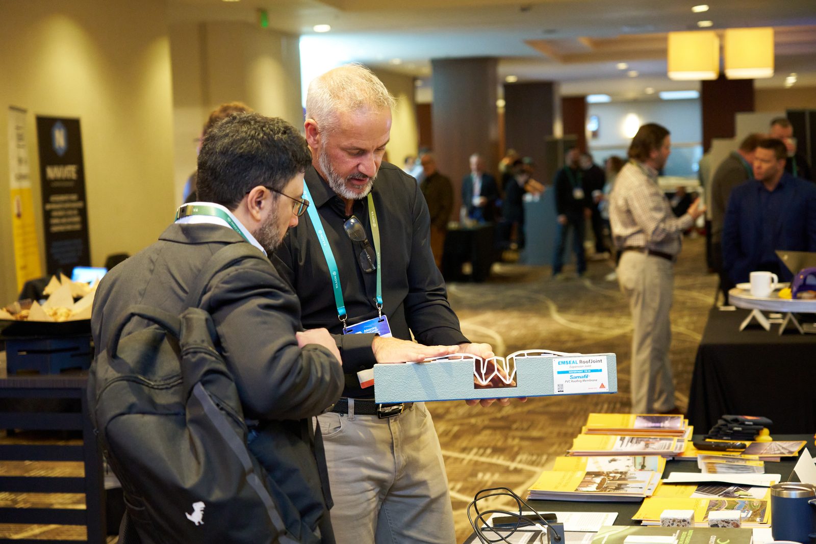 Attendee and exhibitor examining a product sample at an exhibitor table